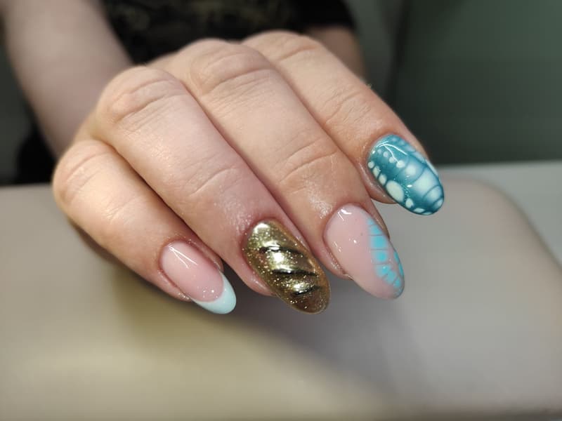 Manicure met gellak in nude, met een gouden en een blauwe accentnagel