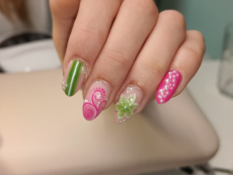 Nagels met een groene 3D-bloem, roze krullen en stippen