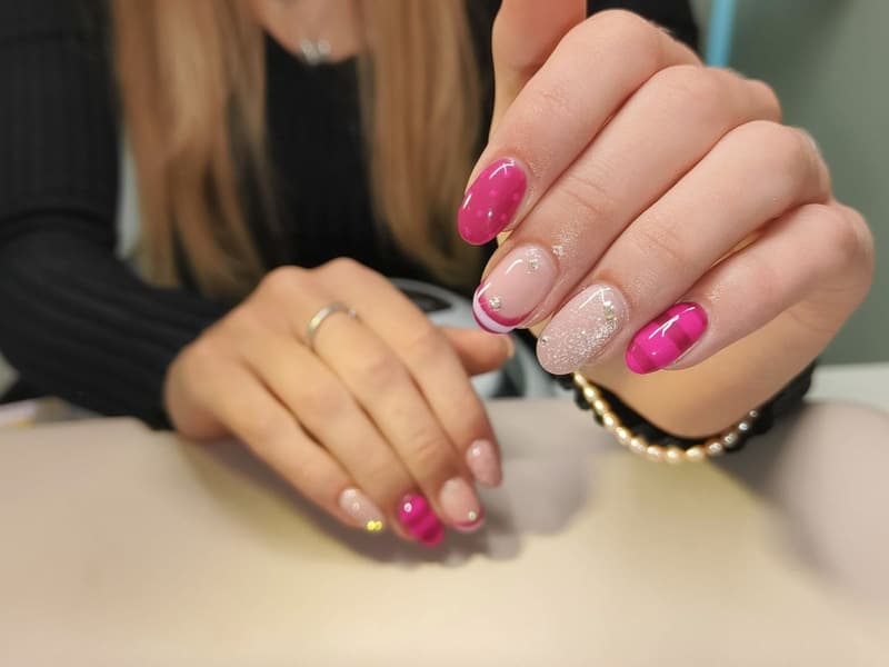 Nagels in fuchsia met een roze french, glitter en een klein steentje