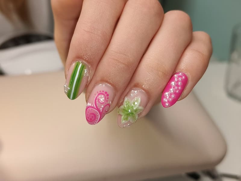 Nagels met een groene 3D-bloem, roze krullen, stippen en een groene streep