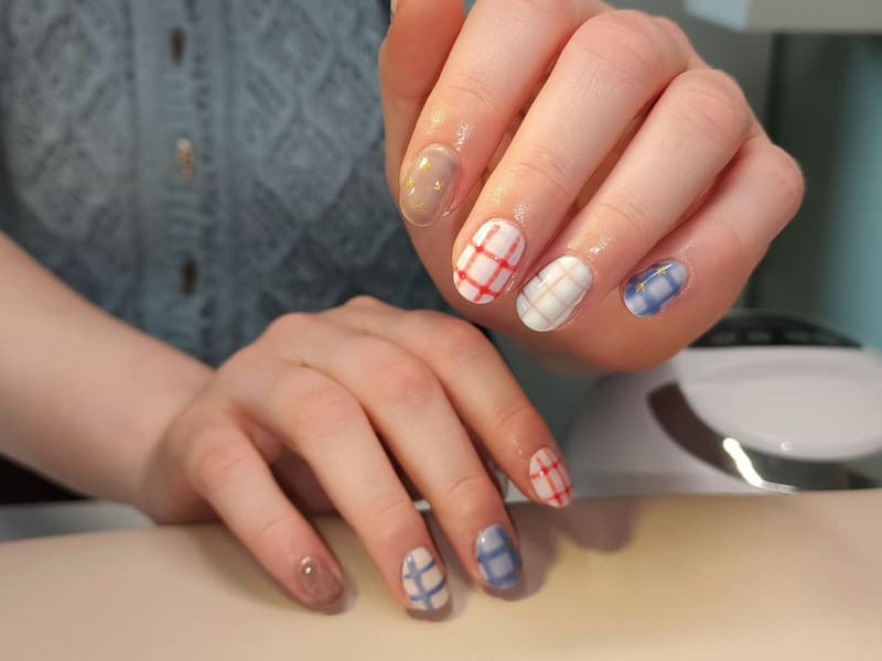 Korte nagels met rode en blauwe ruitjes op een witte basis